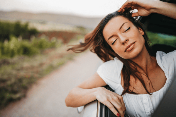 woman taking deep breath out car window