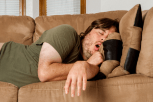 man sleeping on couch with mouth open