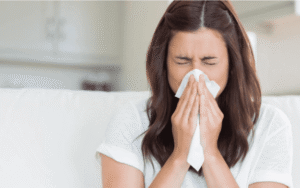 Woman blowing her nose due to persistent nasal congestion, illustrating whether nasal polyps can cause constant nasal congestion.