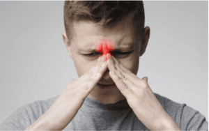 Man experiencing recurrent sinus pressure and inflammation, illustrating ongoing sinus infection symptoms.